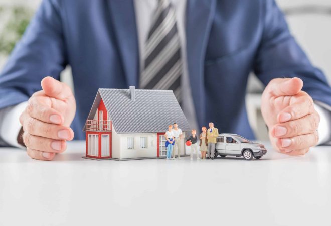 Insurance house, car and family health live concept. The insurance agent presents the toys that symbolize the coverage.