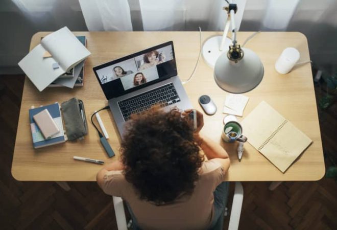 Flattening the curve: a happy woman sitting at home and talking to her friends or colleagues in a meeting using her laptop computer.