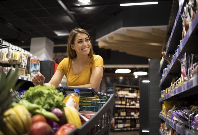 Woman with shopping cart buying food at supermarket.