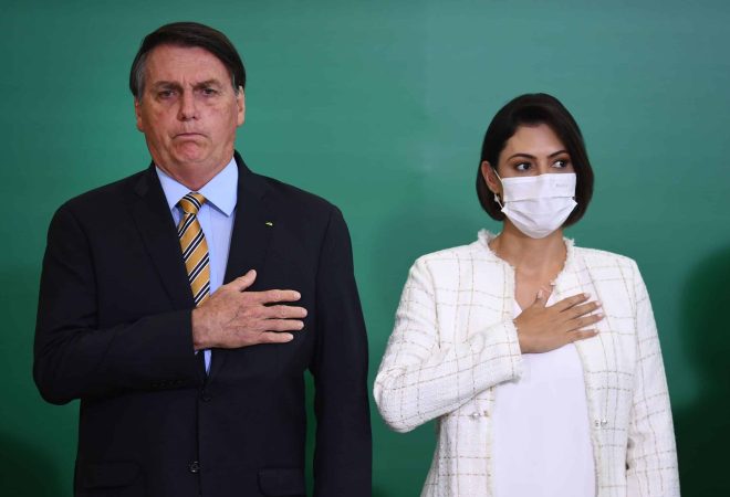 Brazilian President Jair Bolsonaro and First Lady Michelle listen to Brazil's national anthem during the commemoration of the 54th anniversary of the creation of Brazil's Tourism Board (EMBRATUR) at Planalto Palace in Brasilia, on November 17, 2020. (Photo by EVARISTO SA / AFP)