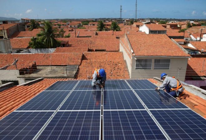 Dois-trabalhadores-instalam-placas-fotovoltaicas-sobre-telhado-para-geração-solar-Foto-Natinho-Rodriguesjpg