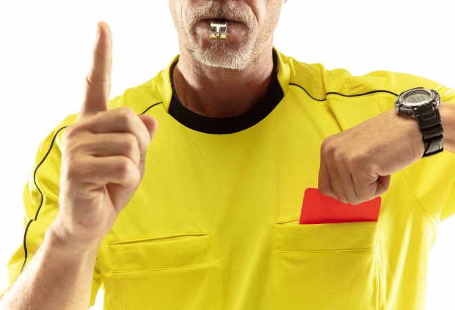 Referee showing a red card to a displeased football or soccer player while gaming isolated on white studio background. Concept of sport, rules violation, controversial issues, obstacles overcoming.