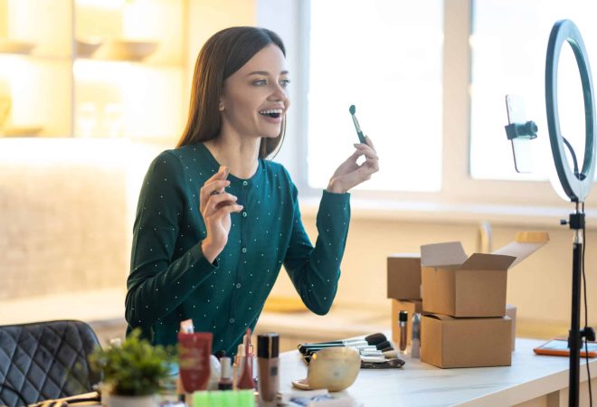 Online beauty class. Young woman in green dress showing make up tips online