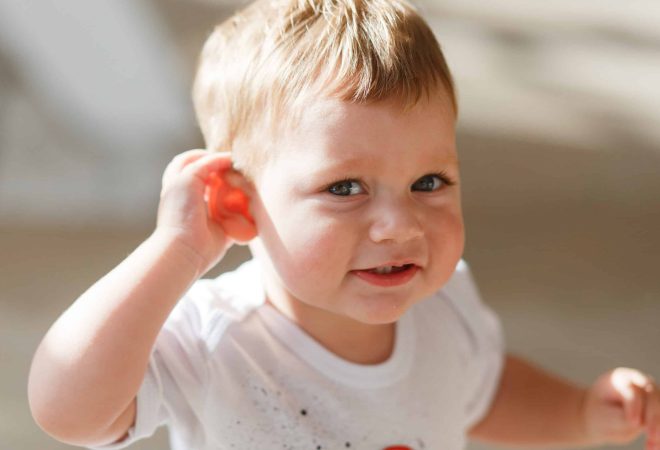 baby boy listens to put a hand to his ear.
