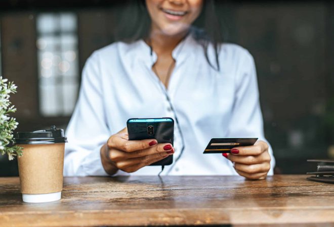 Pay for goods by credit card through a smartphone in a coffee shop.