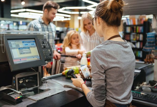 Beautiful family standing at the cash counter buying groceries at the supermarket
