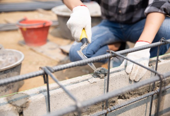 Bricklayer worker installing brick masonry on exterior wall with trowel putty knife
