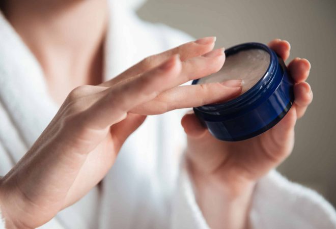 Close up of a young woman hands holding jar of cream indoors