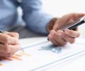 Closeup of business man working with diagram. Map infographics study. Technology and information concept. Cropped view.
