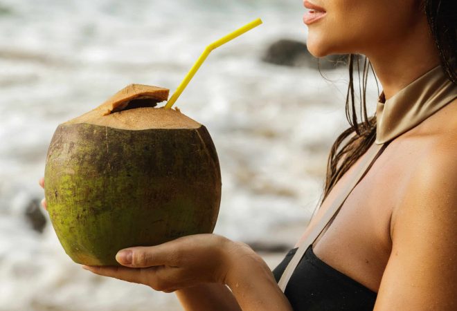 Woman with a coconut drink on the beach