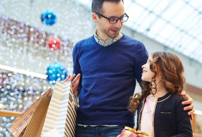 Adorable girl looking at her father while moving in the mall