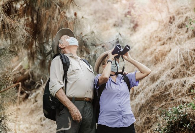 Couple appreciating the beauty of nature with binoculars during the new normal