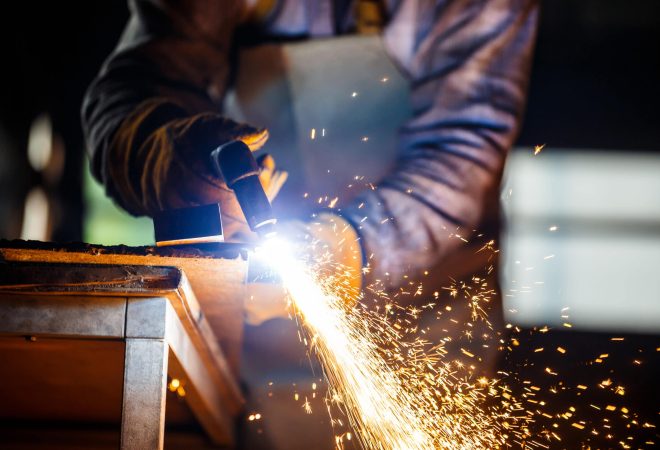 Worker cutting metal with plasma equipment on plant.
