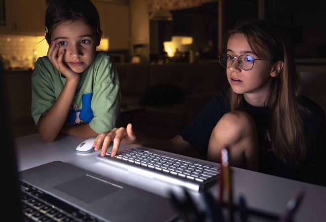 Two young girls at the computer at night. High quality photo