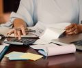 Hands of female entrepreneur working with bills and documents