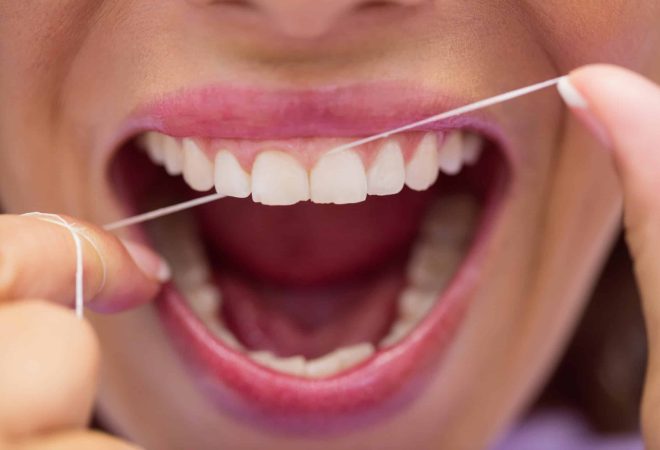 Close-up of female patient flossing her teeth in dental clinic