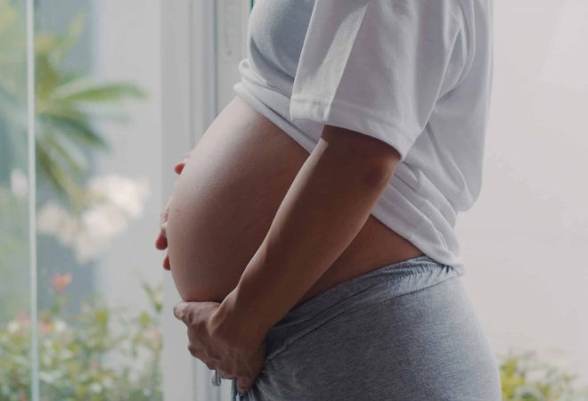 Young Pregnant woman holding her belly talking with her