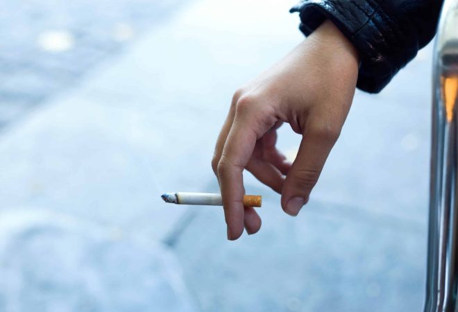 Close up of womans hand with cigarette in the street.
