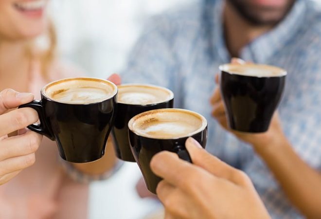 Group of happy friends toasting cup of coffee in cafe