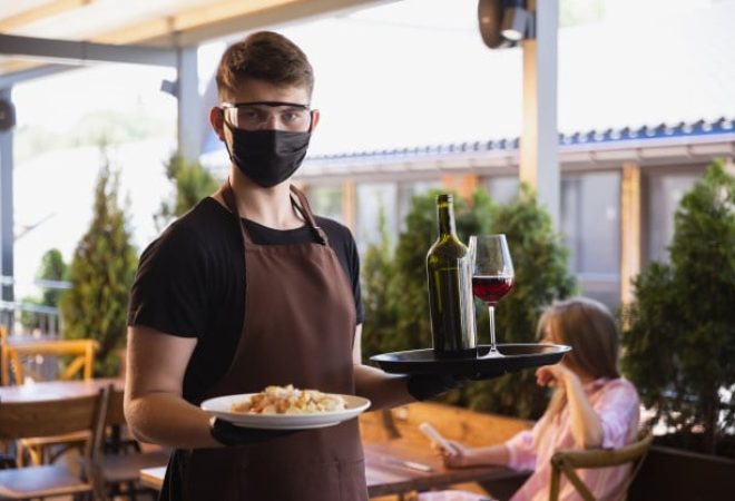 garcom-trabalha-em-um-restaurante-com-uma-mascara-medica-luvas-durante-uma-pandemia-de-coronavirus_155003-13957