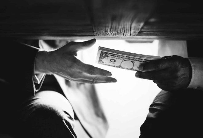 Hands passing money under the table corruption and bribery