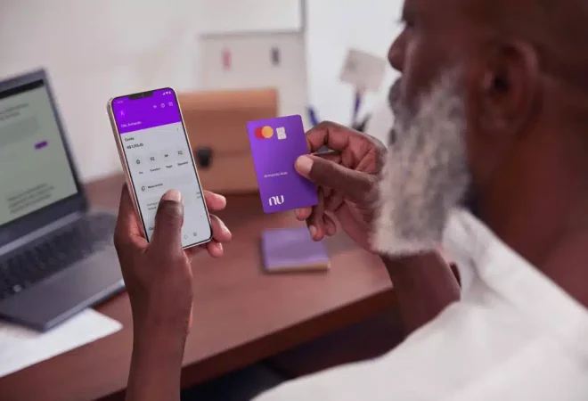 homem-consultando-aplicativo-nubank-no-celular-e-segurando-cartao-de-credito