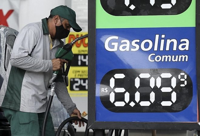 An employee works at a gas station in downtown Sao Paulo, Brazil, on December 31, 2021. - Even though 2021 had been anticipated as the year of economic recovery in Brazil, high inflation and the complications derived from the pandemic, are forcing Brazilians to get more and more into debt, despite the rising interest rates. (Photo by Filipe ARAUJO / AFP)