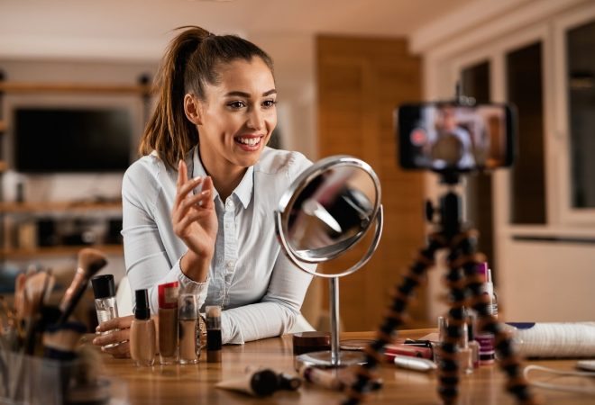 Smiling female influencer talking about beauty products while vlogging from home.
