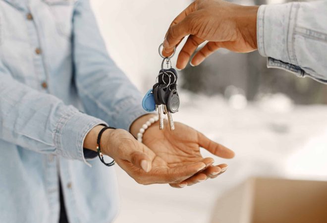 Young couple moving in to new home together. African american couple with cardboard boxes. Woman hold keys.