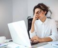Young beautiful businesswoman thinking, working with laptop at workplace in office.