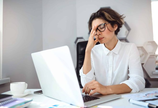 Young beautiful businesswoman thinking, working with laptop at workplace in office.