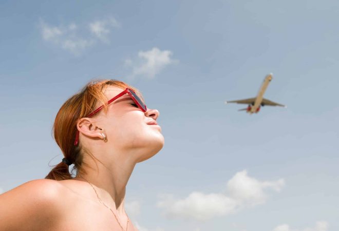 Young Woman looking at an airplane in the sky