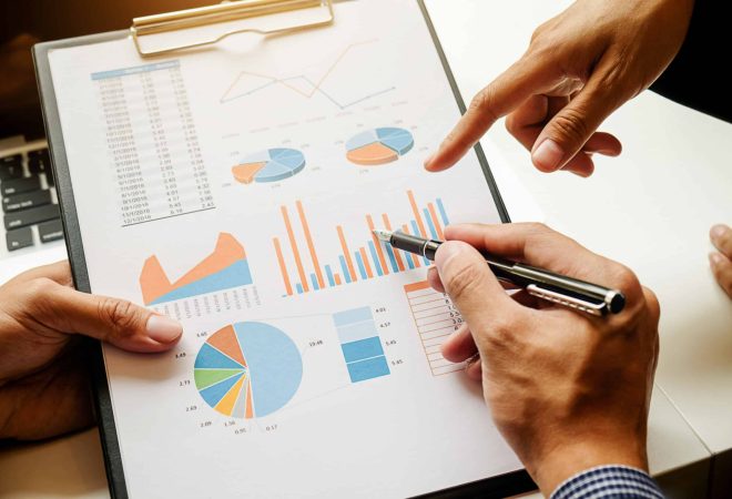Business concept. Business people discussing the charts and graphs showing the results of their successful teamwork. Selective focus.