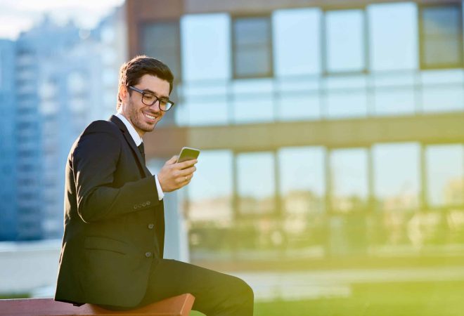 Young broker texting in smartphone outdoors