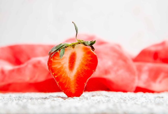 Strawberries on a red cloth and white textured background. side view.