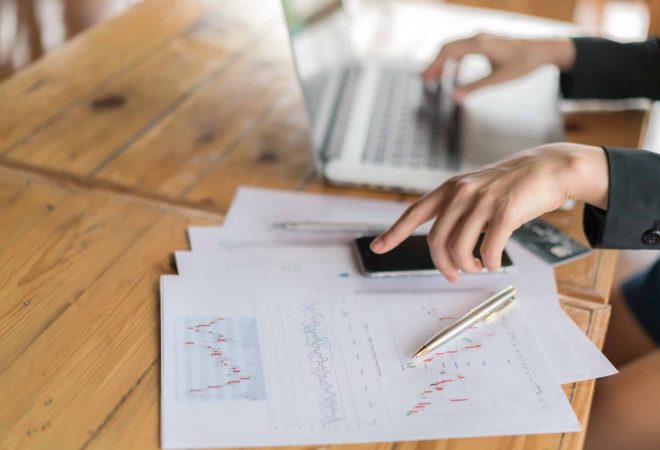 Business woman hand with Financial charts and laptop on the table