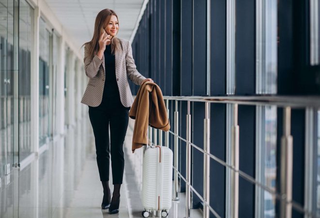 Business woman in terminal with travel bag talking on phone