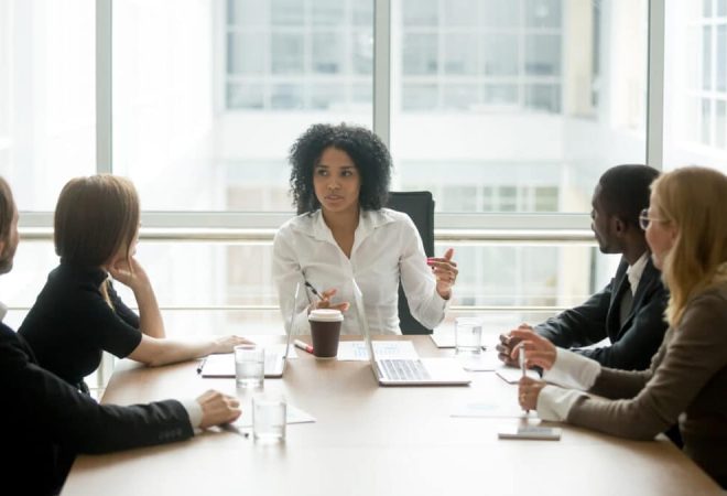 Black female boss leading corporate multiracial team meeting talking to diverse businesspeople, african american woman executive discussing project plan at group multi-ethnic briefing in boardroom