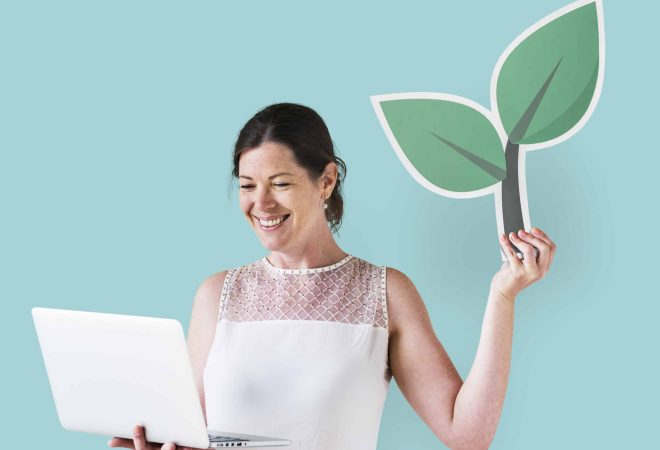 Woman holding a plant icon and using a laptop