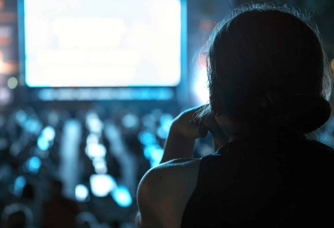 Sitting woman watching football in a public place at night