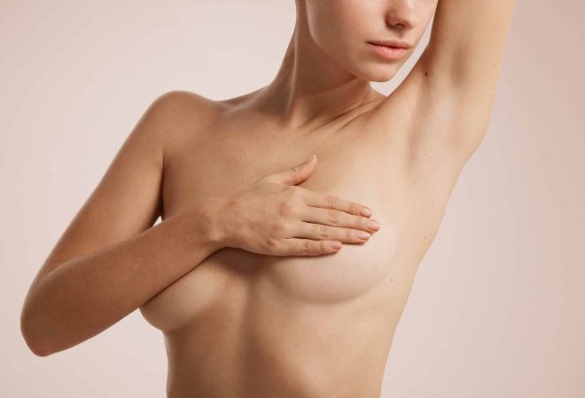 Closeup cropped portrait young woman with breast pain touching chest colored isolated on background