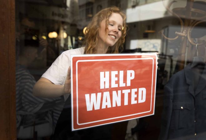 person-with-hiring-sign-by-window