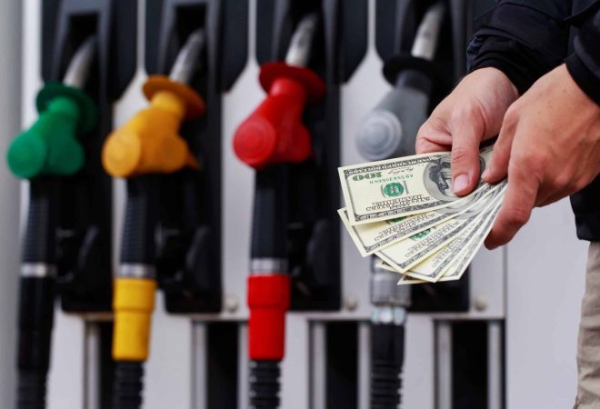 Dollars in a hands on the background of fuel pistols