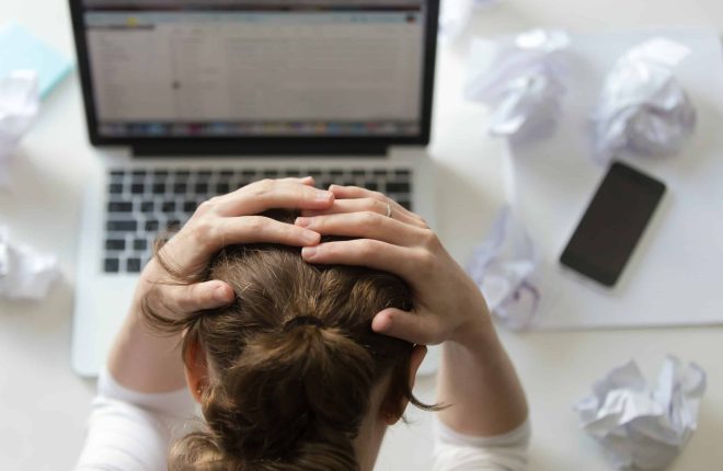Top view portrait of a woman grabbing her head in despair at the desk near the laptop. Education, business concept photo. Lifestyle