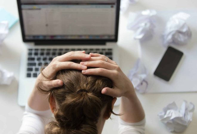 Top view portrait of a woman grabbing her head in despair at the desk near the laptop. Education, business concept photo. Lifestyle