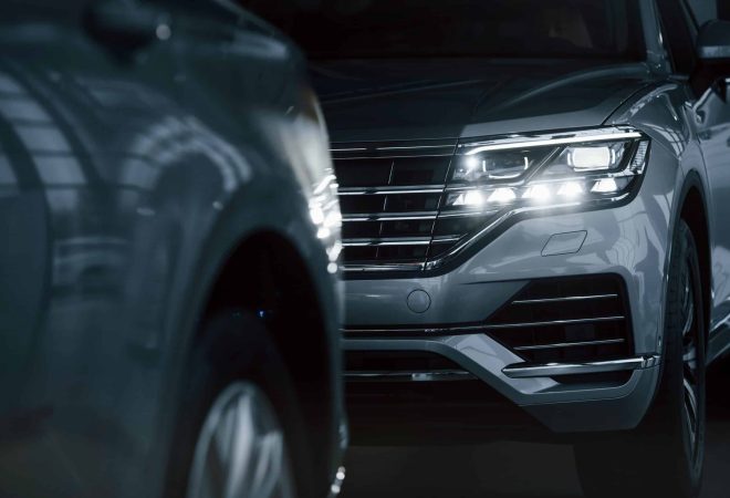 Powerful headlights. Particle view of modern luxury cars parked indoors at daytime.
