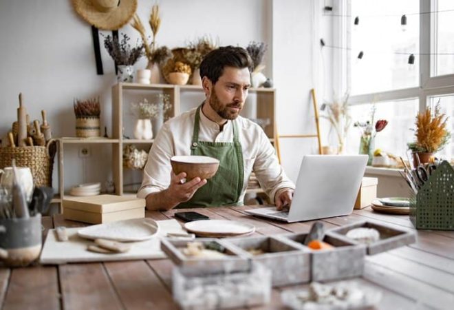 proprietario-de-uma-loja-de-ceramica-adulto-usando-um-laptop-enquanto-trabalha-na-loja_161094-23694