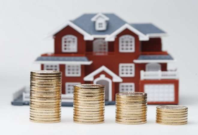 RMB coins stacked in front of the housing model (house prices, house buying, real estate, mortgage concept)