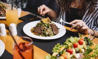 side view of a woman eating beef meat salad with vegetables and corns