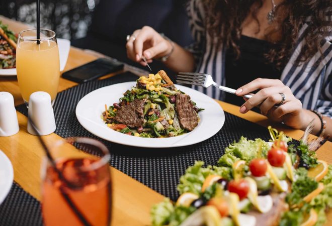 side view of a woman eating beef meat salad with vegetables and corns